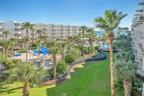 A resort with multiple-story buildings, a pool area, and palm trees.
