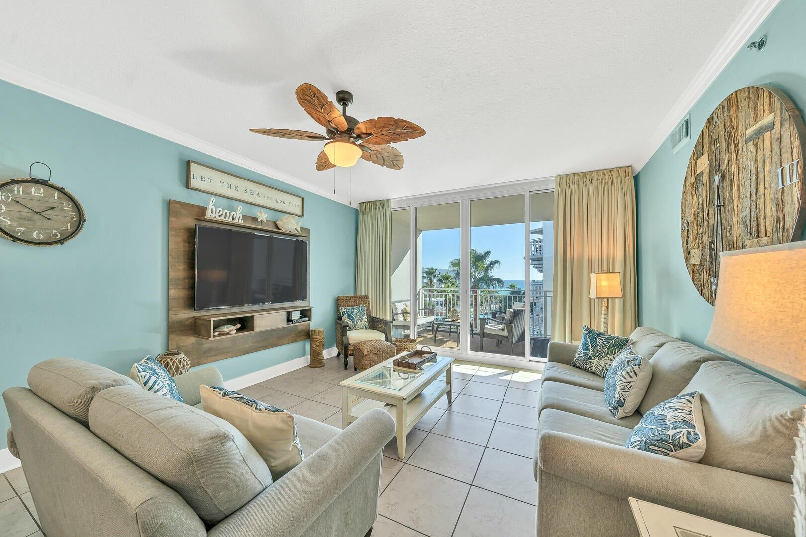 Un soggiorno con una grande TV a schermo piatto, una ventola a soffitto e vista sull'oceano.