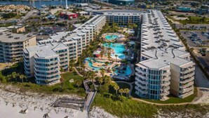 Un resort con varias torres, un área de piscina central y una playa.