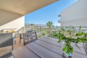 A balcony with wicker furniture, a table, and a vase of flowers.