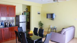 A compact kitchen with wooden cabinets, a refrigerator, and a dining area with a glass table and chairs. - Cozy one bedroom apartment (Union)