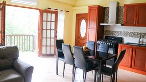 A kitchen with wooden cabinets, a gas stove, and a dining area with a table and chairs. - Cozy one bedroom apartment (Union)