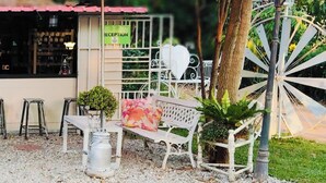 A reception area with a sign, a bench, a small table, and a decorative fence. - Village Homestay (Kumphawapi)