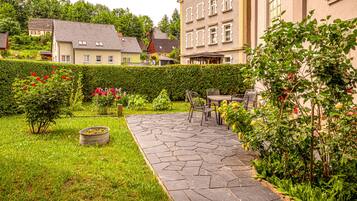 Ein Innenhof mit einem Kiesweg, Sitzgelegenheiten im Freien und einer Hecke.