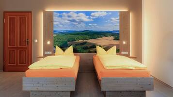 Ein Zimmer mit zwei Betten und Blick auf eine malerische Landschaft durch ein großes Fenster.