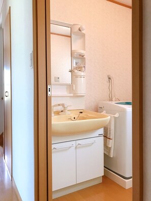 Une petite salle de bain comprenant un lavabo, un miroir et un petit meuble de rangement.
