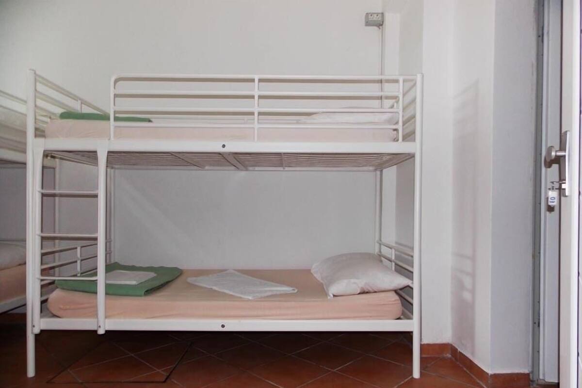 A bunk bed with a green mat and a pillow on the lower bunk.