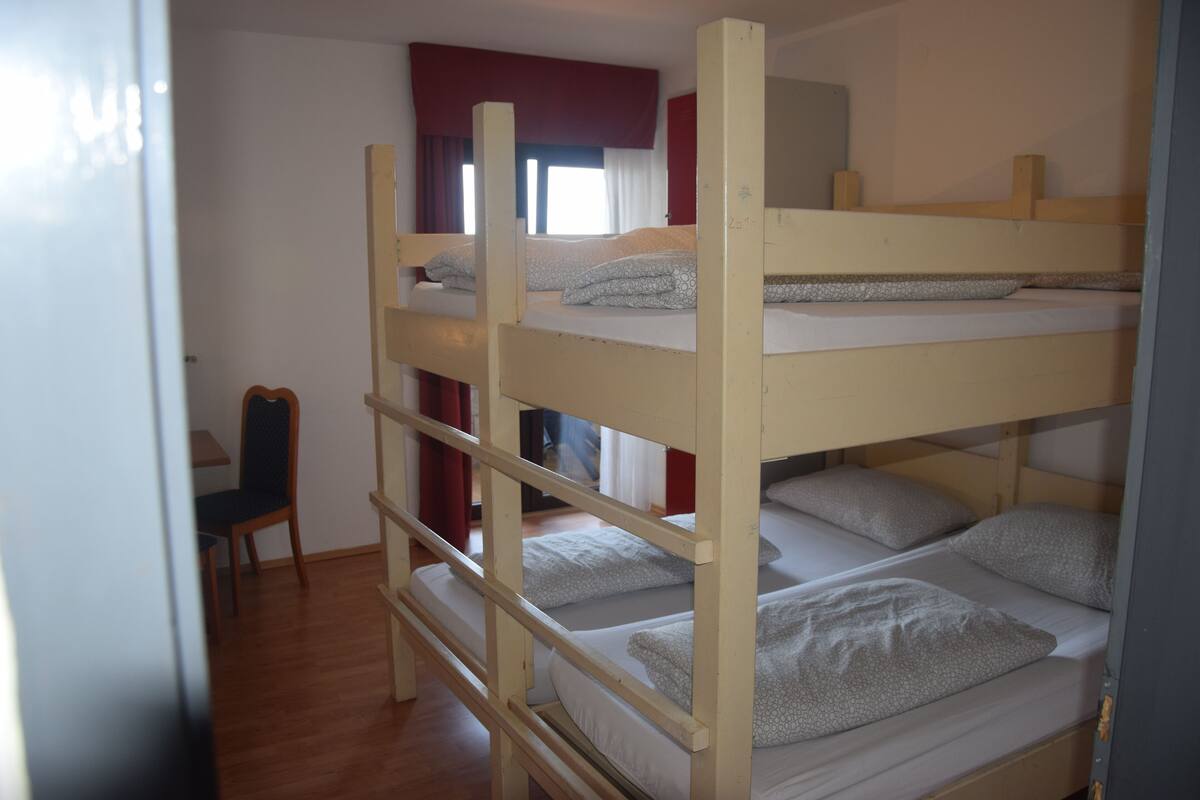 A bunk bed room with a desk and chair.