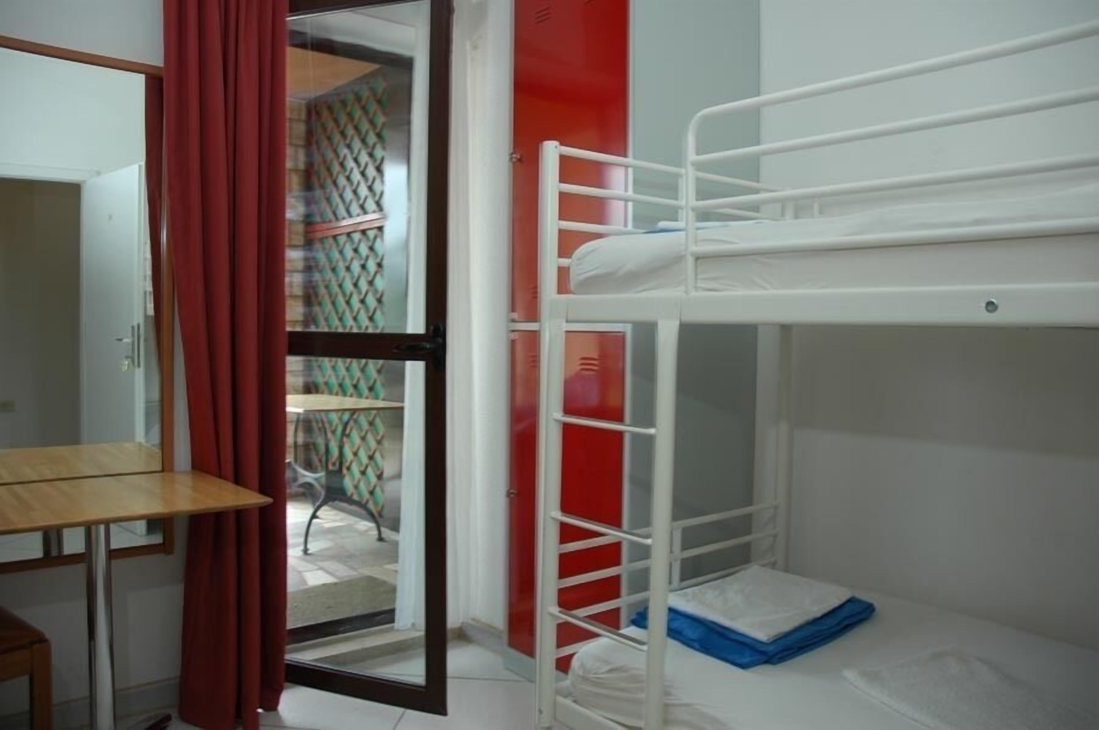 A bunk bed room with a wooden table and a red curtain.