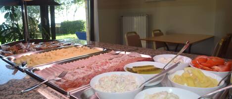Un buffet amb diferents plats, incloent carns, amanides i fruita.