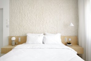 A neatly made bed with white bedding, a wooden headboard, and a bedside table with a lamp and a bowl of fruit. - Hotel Hello Plovdiv (Plovdiv)