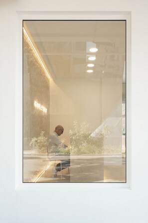 A modern hotel interior with a reception desk, a man sitting at a table, and a visible sign indicating the hotel's name. - Hotel Hello Plovdiv (Plovdiv)