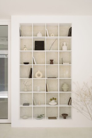 Une étagère blanche, ornée de divers objets décoratifs et de livres.
