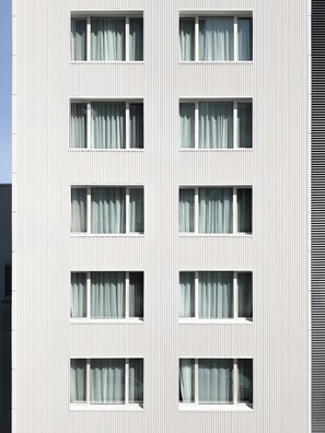 A multi-story building with a uniform facade, featuring evenly spaced windows with white frames and curtains. - Hotel Hello Plovdiv (Plovdiv)