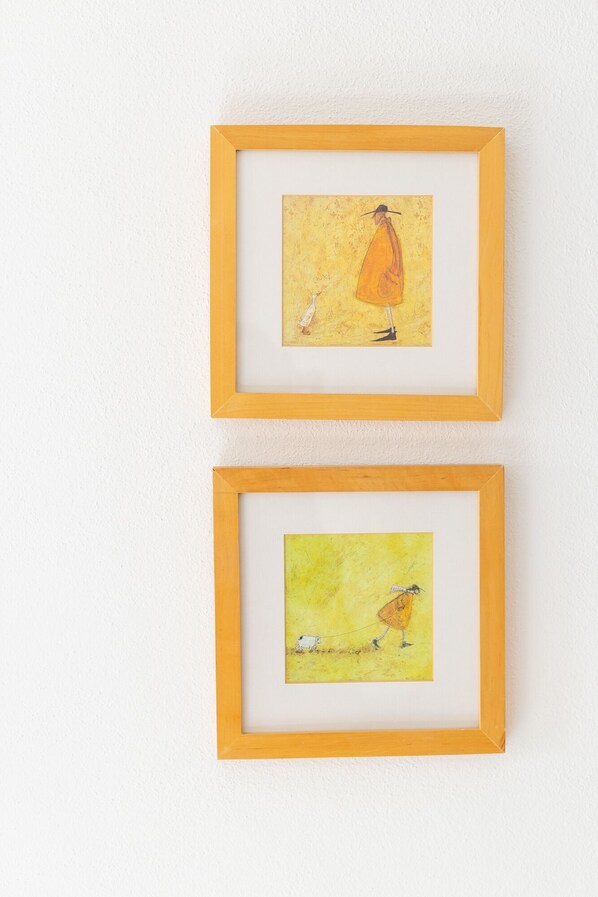 Deux œuvres d’art encadrées sont accrochées à un mur blanc.
