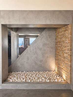 A modern interior with a concrete structure, a pebble-filled area, and a stone wall.