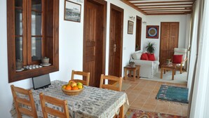 A dining area with a table set for two, a fruit bowl, and wooden chairs.