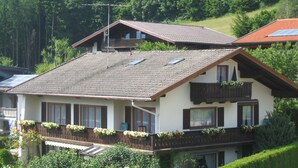 A two-story chalet with a sloped roof, wooden balcony railings, and flower boxes. - Ferienwohnung Rauschberg Balk., Küche, 1 Schlaf- u. 1 Wohn-/schlafz., max 4 P (Ruhpolding)