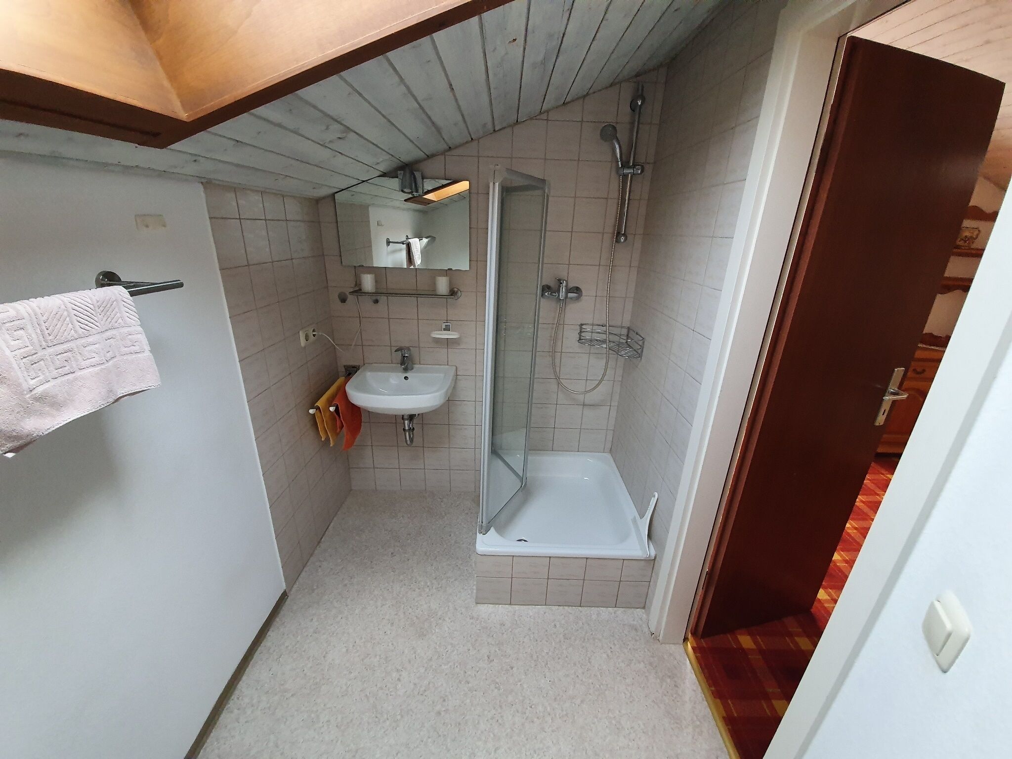 A small bathroom with a sink, mirror, and shower.