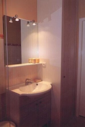 A bathroom with a round sink, a mirror, and a shelf with toiletries. - Charming Apt. in a villa ideally located in a pine woods near the sea (Var)