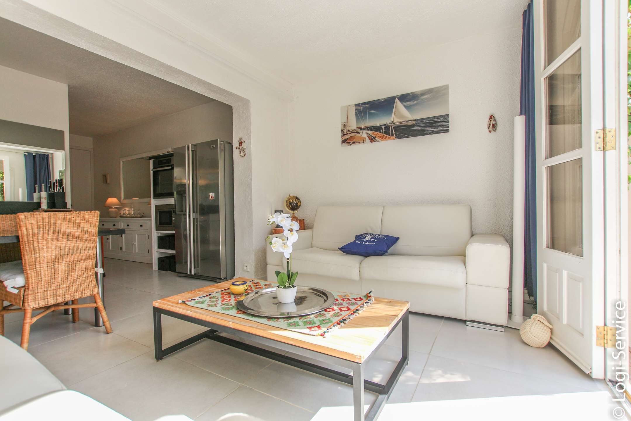 A modern living room with a sofa, a dining table, and a kitchen area in the background.