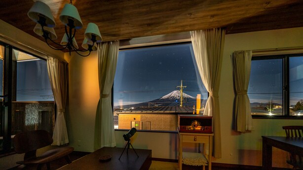 Una habitación con un amplio ventanal que ofrece vista a una montaña de noche.