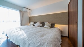 Un dormitorio moderno con una cama grande, cabecera de madera y vistas a la ciudad desde la ventana.