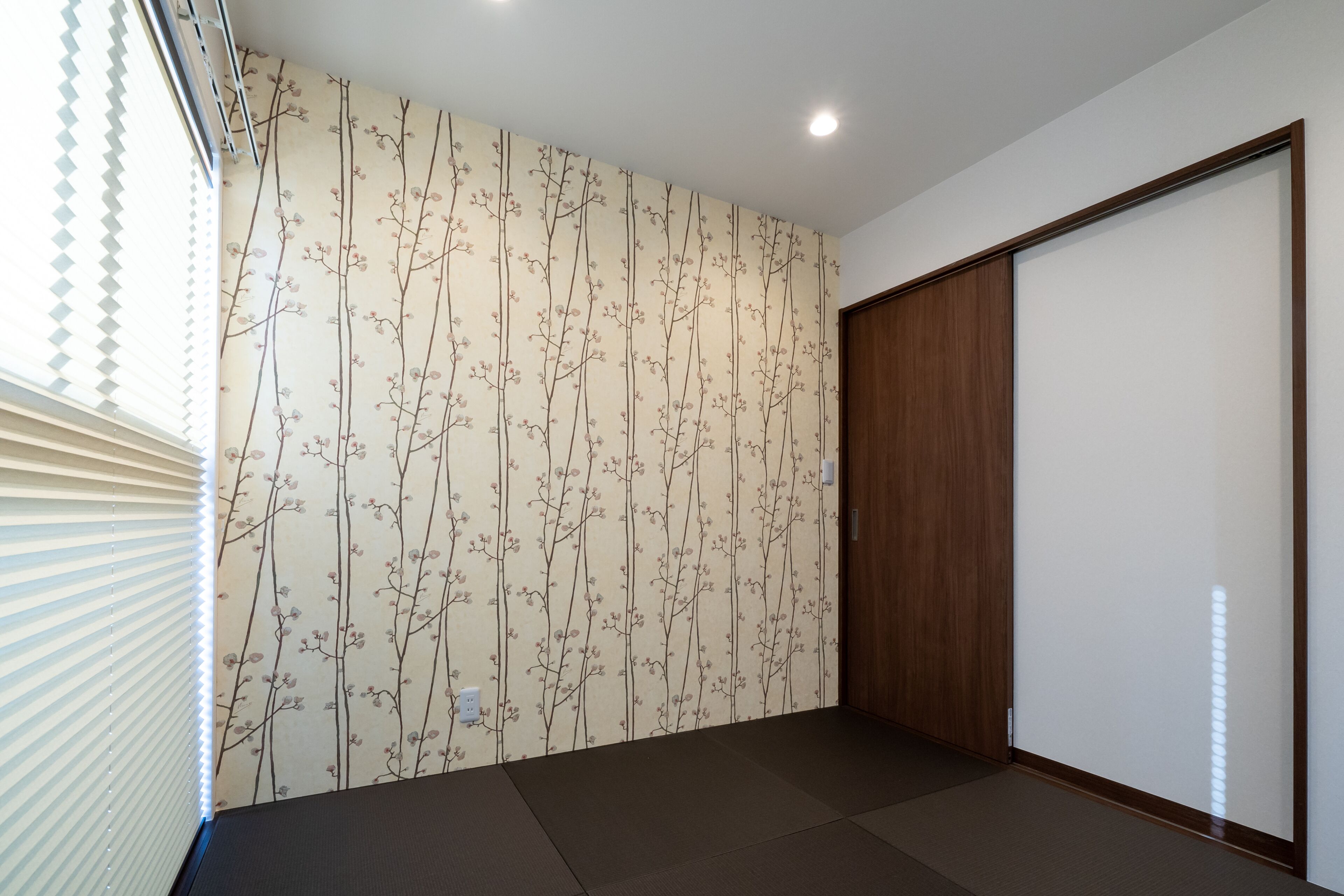 Um quarto com papel de parede estampado, uma porta deslizante e uma janela com persianas.
