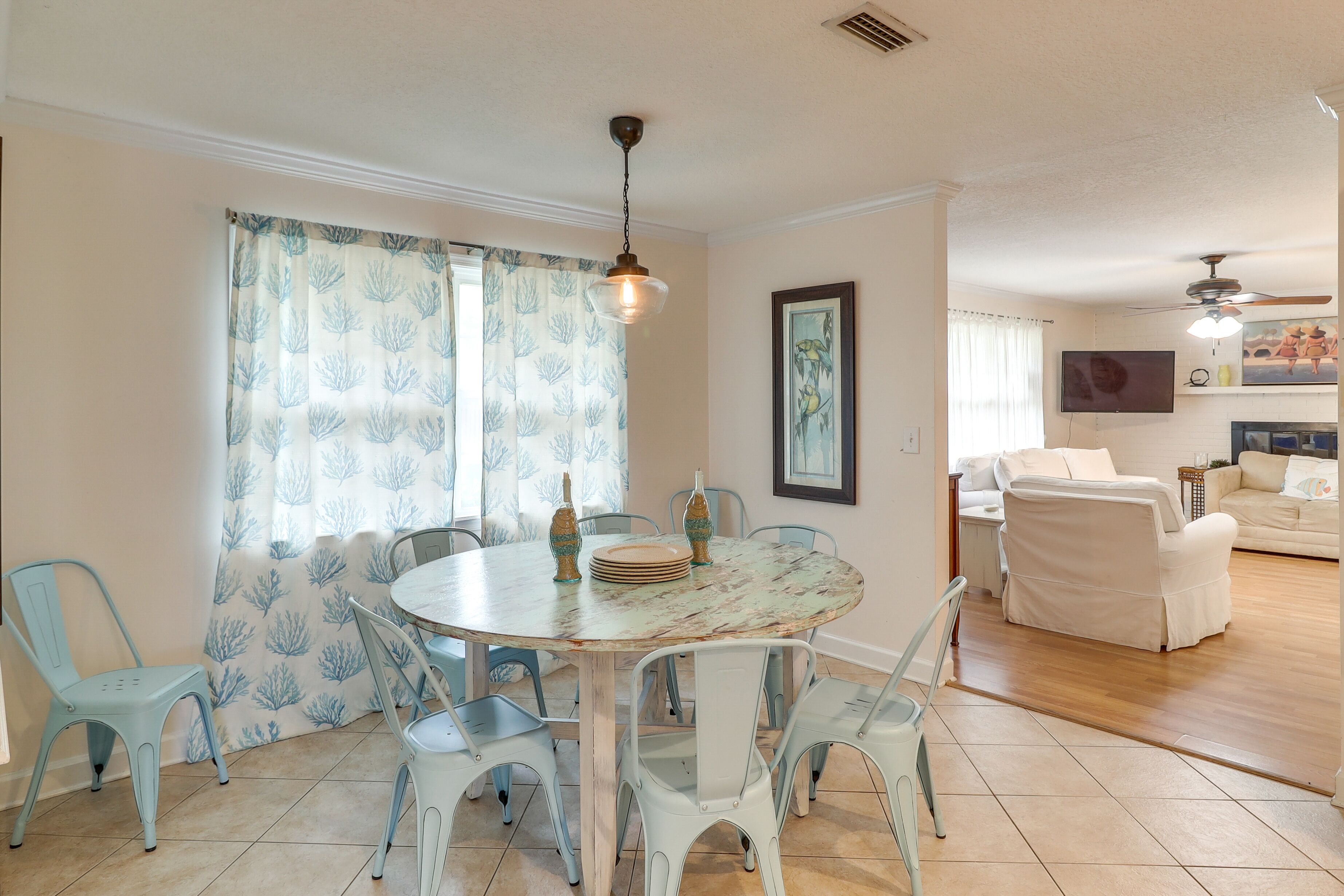 A dining area with a round table, chairs, and a ceiling fan.