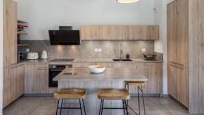 Una cucina moderna con mobili in legno, un'isola centrale con sgabelli e luci a sospensione.