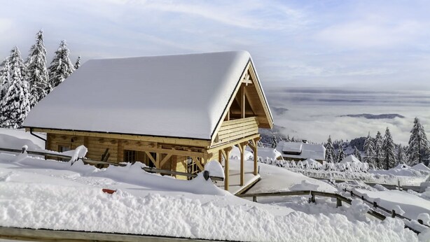 A wooden cabin with a snow-covered roof, surrounded by a snowy landscape and trees. - Hütte Buchfink by Interhome (Sirnitz - Hochrindl)