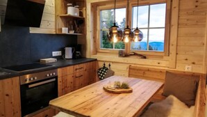 A cozy cabin-style kitchen with wooden walls, a black countertop, and a wooden dining table. - Hütte Buchfink by Interhome (Sirnitz - Hochrindl)