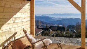 A wooden cabin with a wooden deck and a chair. - Hütte Buchfink by Interhome (Sirnitz - Hochrindl)