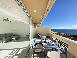 Ein Balkon mit Essbereich, Blick auf das Meer, einer Couch und einer Lampe.