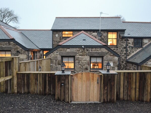 A stone building with multiple windows, a wooden fence, and a gate.