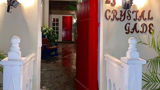 Une entrée avec un sol mouillé, une porte rouge et le numéro 23 peint sur le mur.