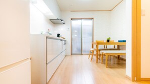 Cozinha moderna com frigorífico, fogão e pia, que dá para um espaço de refeições com mesa e cadeiras.