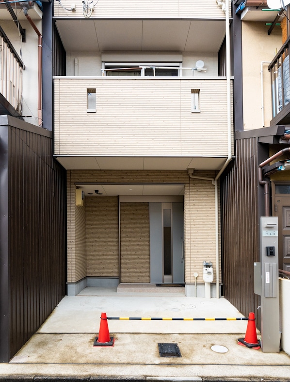 A modern building with a flat facade, a visible elevator, and a gated entrance with a security barrier.