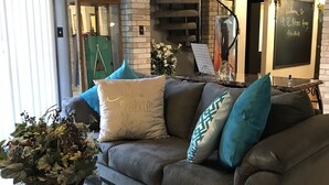 A cozy living room with a leather sofa, decorative pillows, a glass coffee table, and a staircase with a metal railing. - Spacious, clean, comfortable home that's relaxing with a warm feeling.<br> (San Antonio)