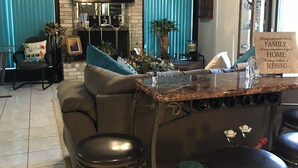 A modern living room with a central island, bar stools, a ceiling fan, and a television. - Spacious, clean, comfortable home that's relaxing with a warm feeling.<br> (San Antonio)