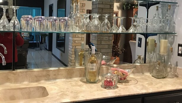 A kitchen with a glass display shelf holding various glassware. - Spacious, clean, comfortable home that's relaxing with a warm feeling.<br> (San Antonio)