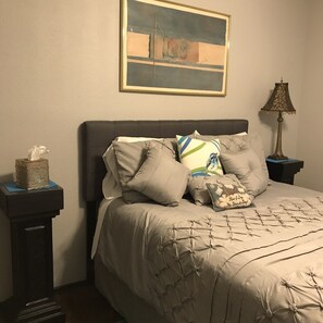 A neatly made bed with a quilted cover, multiple pillows, a bedside lamp, and a tissue box on a nightstand. - Spacious, clean, comfortable home that's relaxing with a warm feeling.<br> (San Antonio)