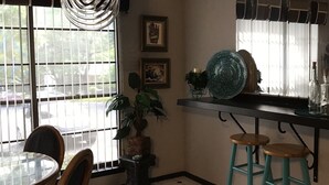 A dining area with a round table and chairs, a hanging light fixture, and a window with blinds. - Spacious, clean, comfortable home that's relaxing with a warm feeling.<br> (San Antonio)
