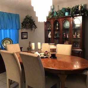 A dining room with a wooden table, four chairs, and a cabinet with glass doors displaying figurines. - Spacious, clean, comfortable home that's relaxing with a warm feeling.<br> (San Antonio)