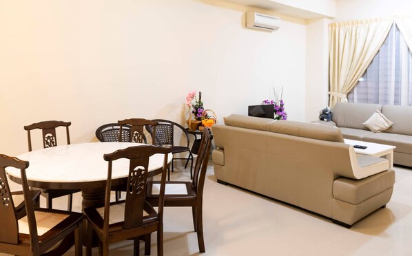 Una sala de estar con una mesa de comedor, sillas, un sofá y un televisor.