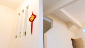Een hal met witte muren, een rode decoratieve versiering en kleine potplanten.