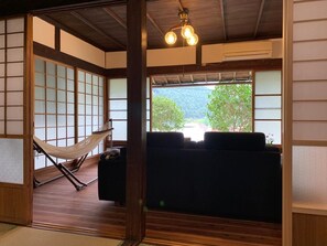 Une pièce de style japonais traditionnel, avec un sol recouvert de tatamis, une basse table en bois, un canapé et un hamac.