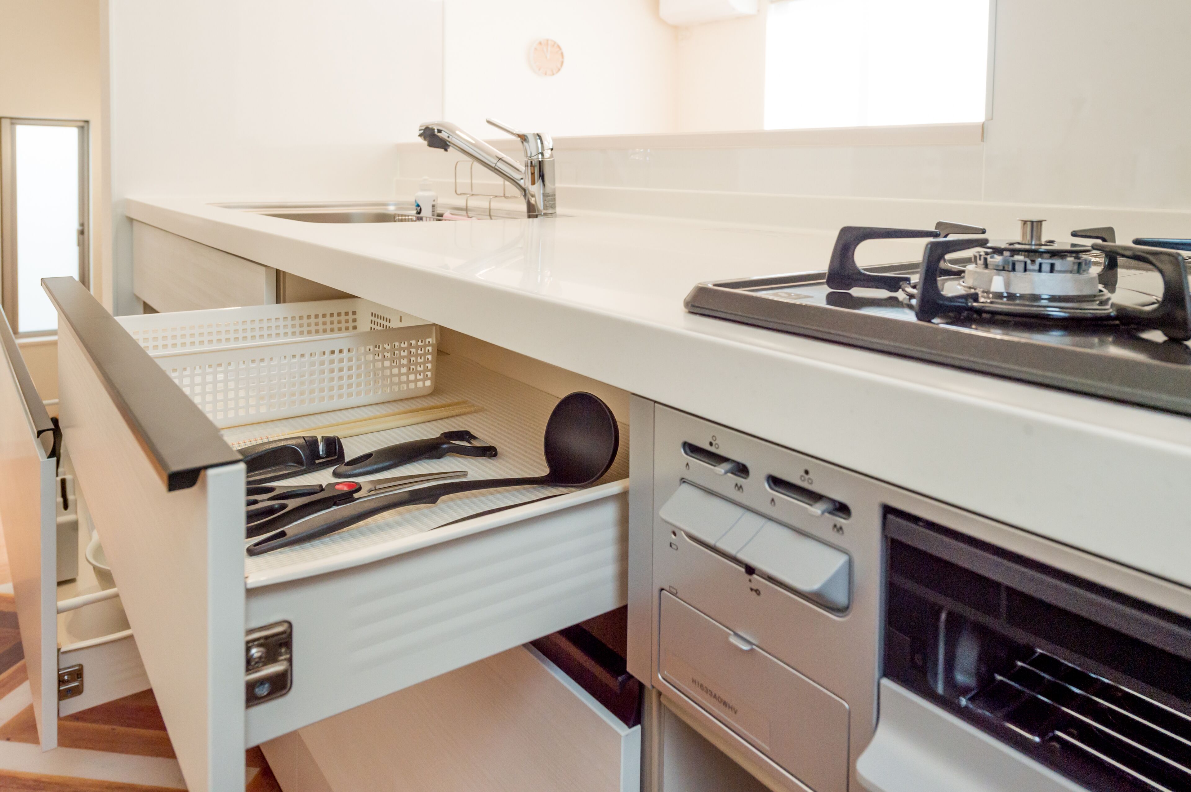 A kitchen with a white countertop, stainless steel sink, and a gas stove.