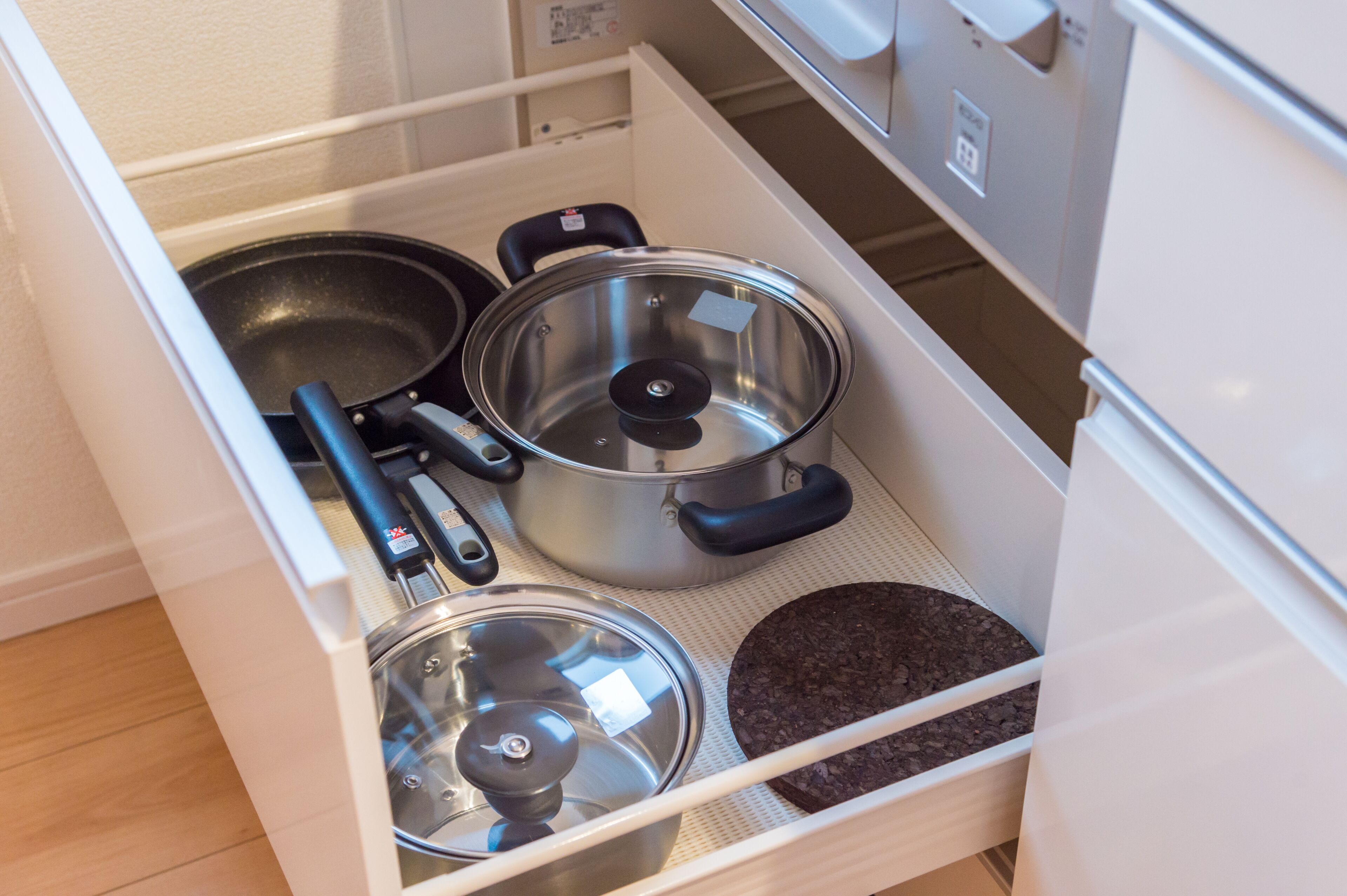 A kitchen drawer with pots, pans, and a cutting board.