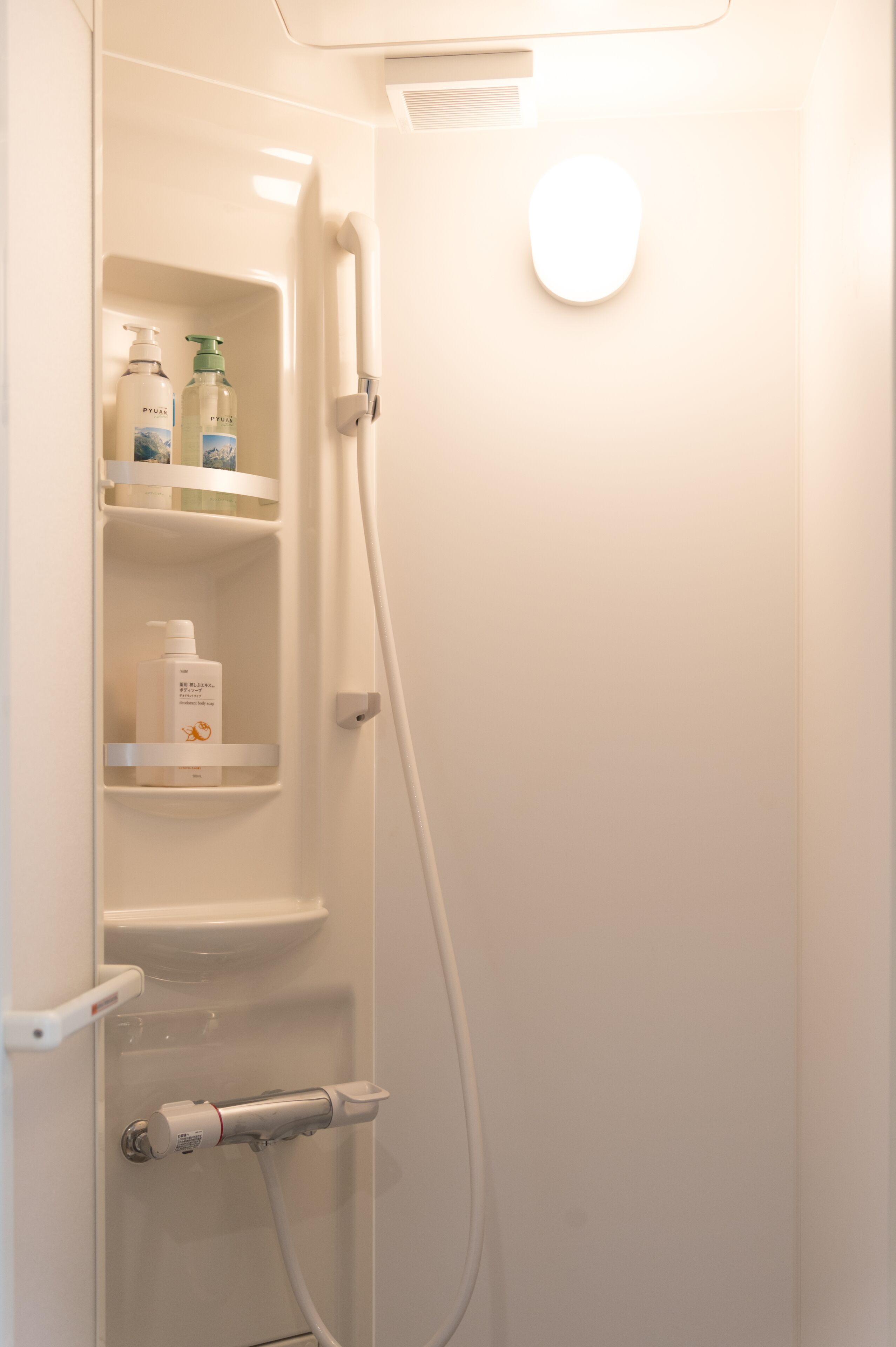Une salle de bain équipée d’une douche, de toilettes et d’une étagère où sont rangés les articles de toilette.
